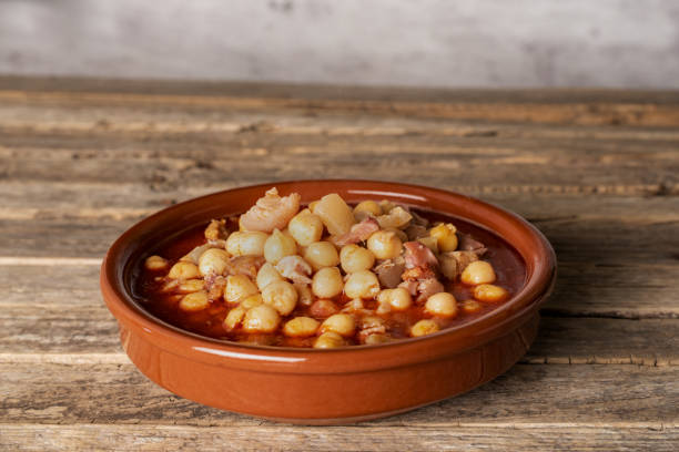 istock Clay dish with tripe and chickpeas, on an old wooden background, diner flat. 1444648820