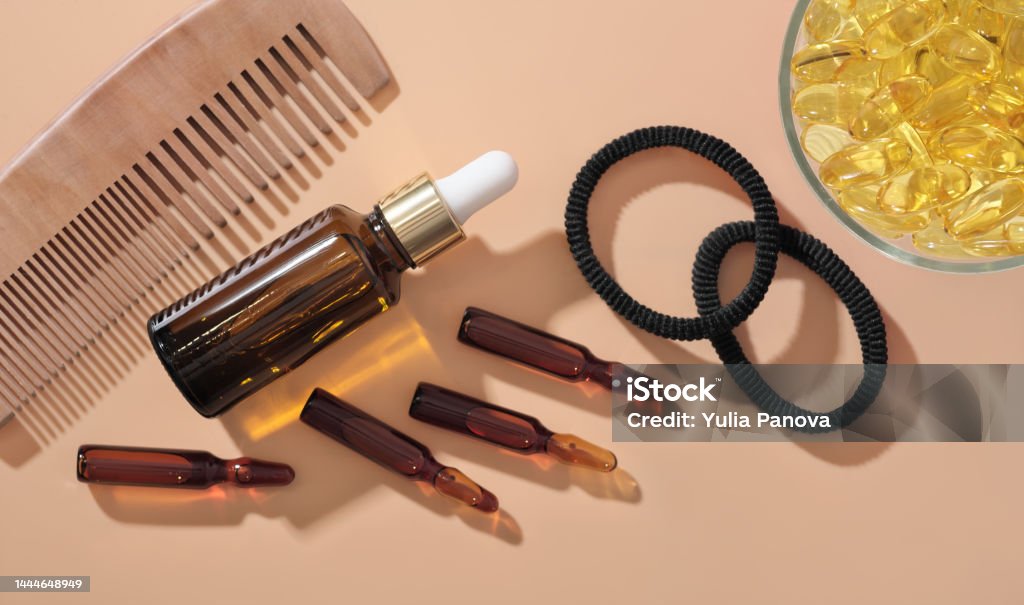 Hair growth ampules and serum solution next to omega 3 capsules and wooden comb on beige background. hair care medical treatment . top view Hair growth ampules and serum solution next to omega 3 capsules and wooden comb on beige background. hair care medical treatment. top view Acid Stock Photo