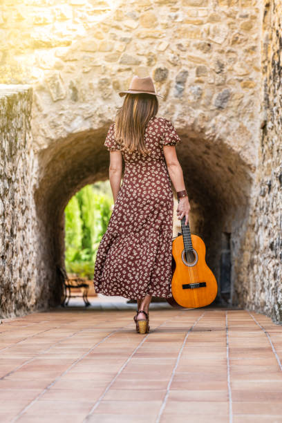 Woman at the door of an Andalusian house plays flamenco guitar and fans herself