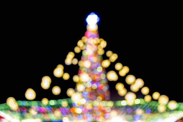 Large New Year's Christmas tree decorated with luminous multi-colored garlands and illumination at night. Christmas tree with flashing lights. Blurred background. New Year and Christmas holidays