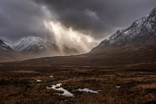 Stunning dramatic Winter sunset sunbeams over landscape of Lost Valley in Etive Mor in Scottish Highlands