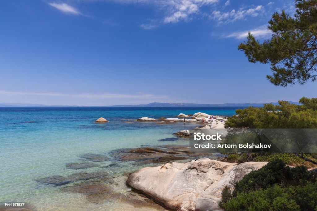 Kavourotrypes or Portokali beach is phenomenal beach on Sithonia with many round or flat rocks as white as little clouds in blue sky, pines come right up to water, Sithonia, Halkidiki, Greece Aquamarine Stock Photo