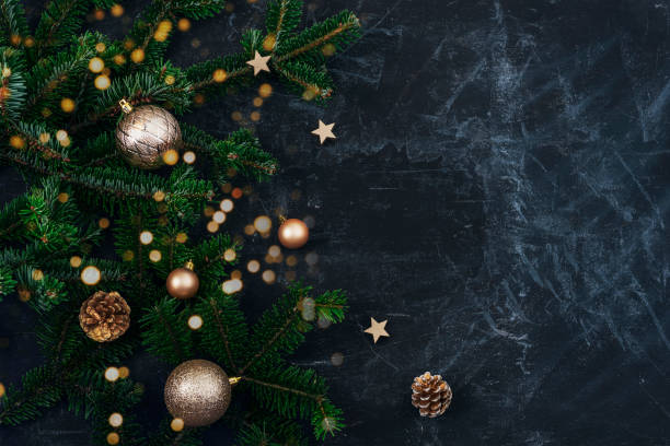 istock Christmas tree branches, golden baubles and pine cones on black background with Christmas bokeh lights. New Year concept. Top view, copy space 1444673725