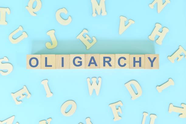istock Oligarchy government form concept. Wooden blocks typography flat lay in blue background. 1444676294