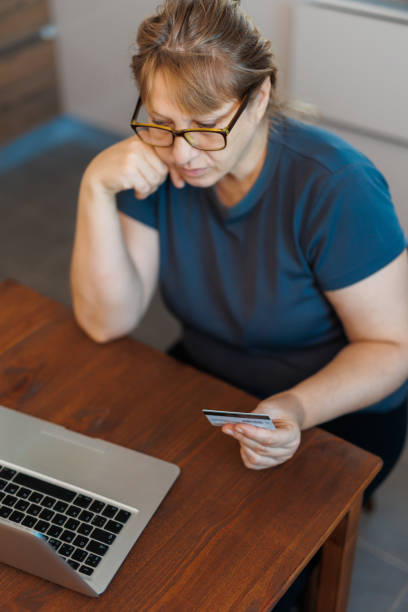 istock Frustrated Retired Senior Woman Sitting On Sofa At Home Using Laptop 1444681577