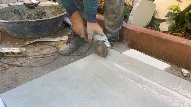 Construction worker cutting granite tile while rebuilding the apartment