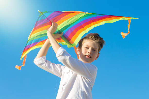 istock A 9 year old boy holds a bright big kite high above his head 1444684355