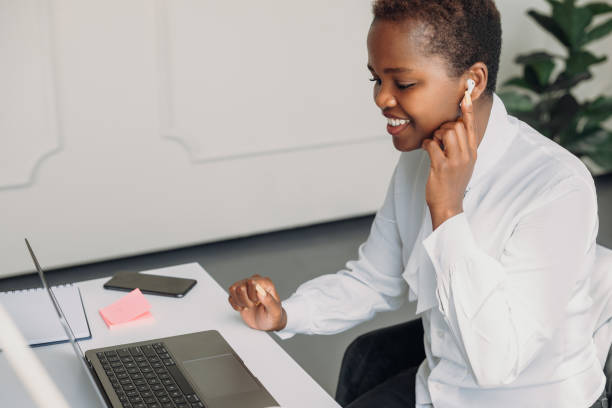 istock Cheerful African businesswoman posing in modern office while having online training. Student studying remotely. Chat with friends on social network. 1444686819