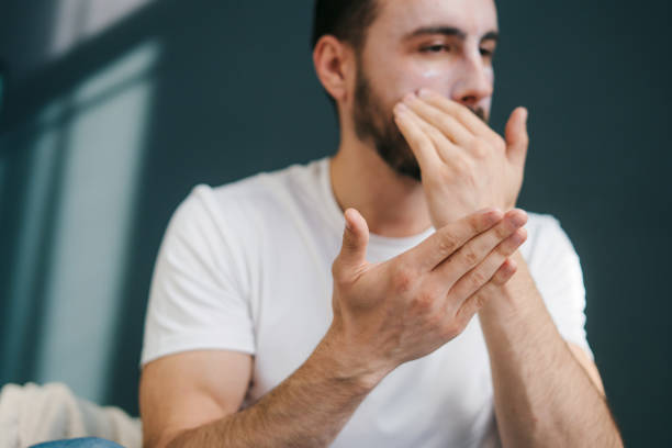 istock Handsome caucasian man applying moisturising cream on face while sitting at home, doing morning routine. Guy touching skin on cheek. Facial treatment, cosmetology, beauty concept. Beauty routine concept. Skincare concept. 1444686842