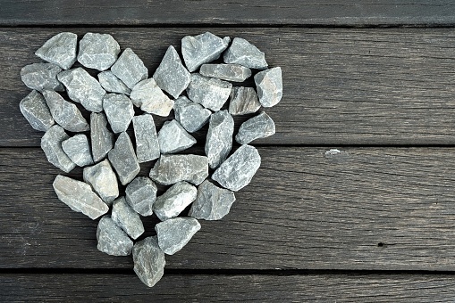 Abstract Stone Heart on Old Wooden Table Background.