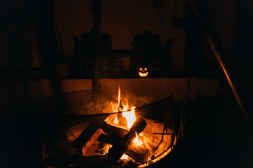 View of the lighting Jack O'Lantern and the campfire outdoors during the October Halloween night