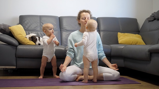A mother of two young children struggles to focus and practice yoga while her twin children continue to harass her. It takes a lot of self-control. Mental health during self-isolation.