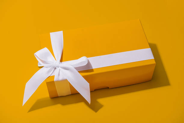 istock Yellow gift box with white ribbon isolated on yellow 1444697004