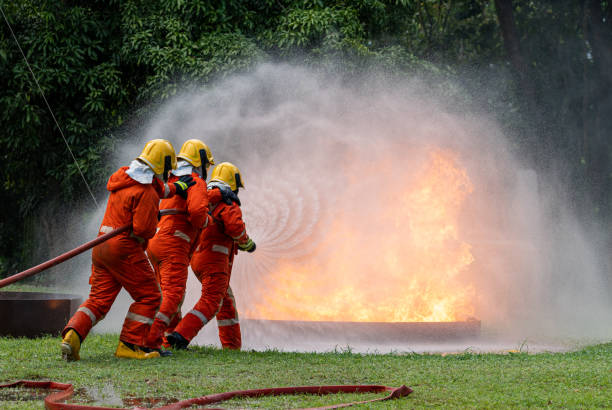 istock Firefighters or Firemen use extinguisher and spray high pressure water from hose to control fire.Firefighter team training to control fire not to spreading out in gas and oil fire accident simulation. 1444699149