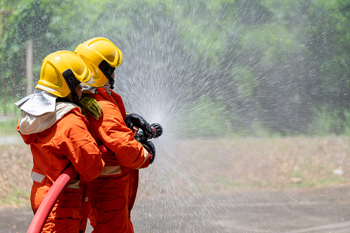 Firefighters or Firemen use extinguisher and spray high pressure water from hose to control fire. Firefighter team training to control fire not to spreading out in gas and oil fire accident simulation.