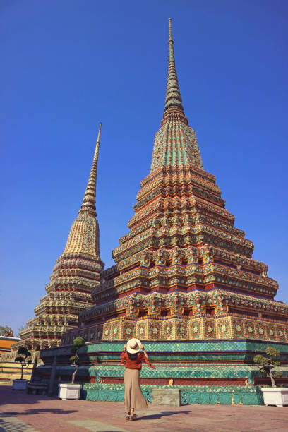 une voyageuse impressionnée par le magnifique stupa phra maha chedi si rajakarn dans le temple du bouddha couché, vieille ville de bangkok, thaïlande - wat pho photos et images de collection