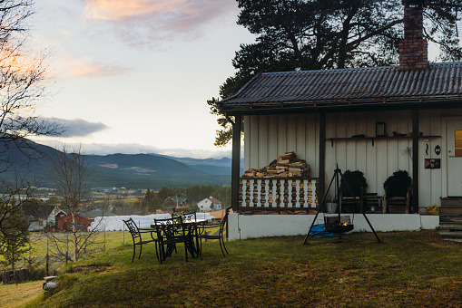 View of the wooden house with a terrace and the grill place in the courtyard with view of the scenic mountains in Scandinavia