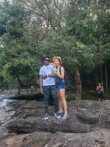 A diverse couple standing beside flowing stream in island