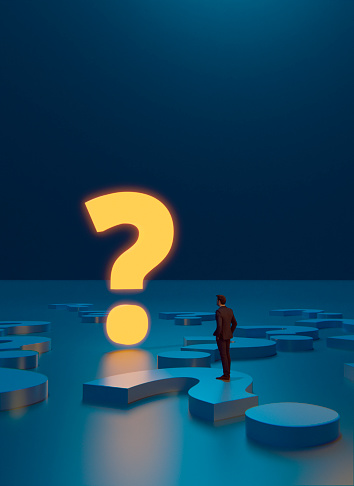 Concepts of making the right decisions and answering the right questions. Man stands in  front of a giant illuminated question mark. He stands on question marks on the floor.