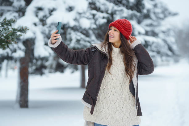 istock Happy woman taking selfie in winter forest. 1444711507