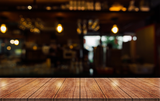 Empty wooden table top with lights bokeh on blur restaurant background.