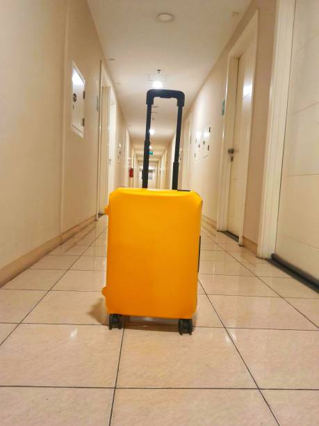 This yellow suitcase was placed in a hallway of the apartment. stock photo