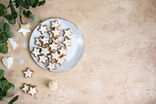 istock Star shape ginger cookies with sugar icing on white plate on beige bckground with Christmas decoration and eucalyptus branch.Copy space 1444739218