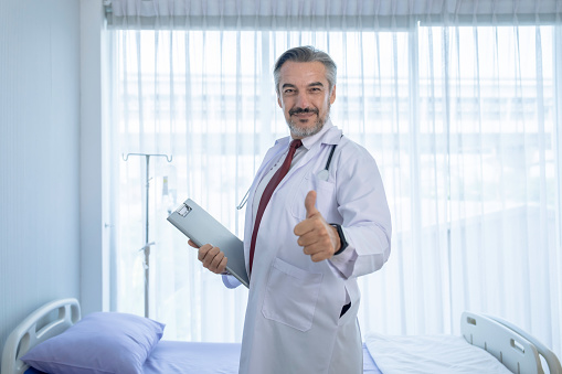 Portrait of confident Caucasian male doctor in white coat standing in hospital.