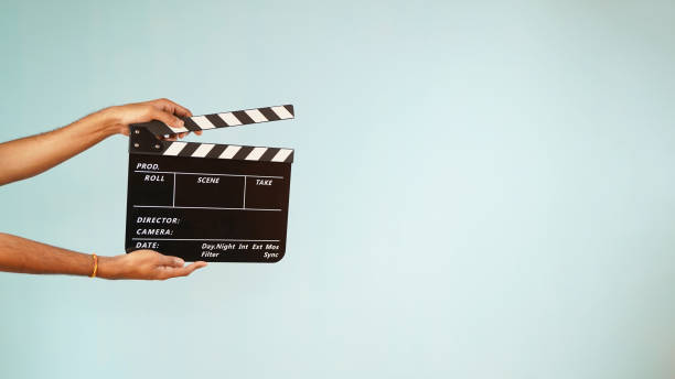 a mão está segurando a placa de clapper ou clapperboard ou ardósia de filme, usado na produção de filmes e cinema, indústria de filmes isolados sobre fundo azul. - clapboard - fotografias e filmes do acervo