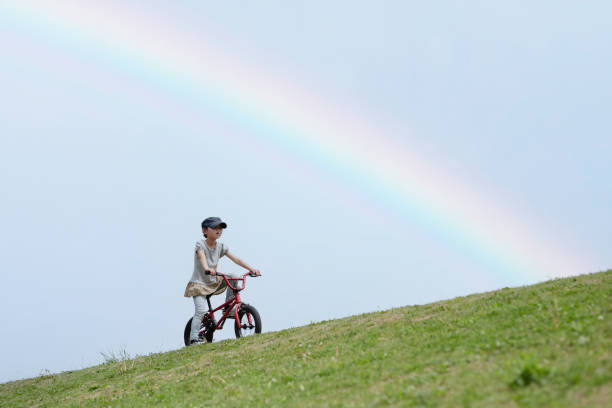 Girl riding a bicycle in a rainbow meadow