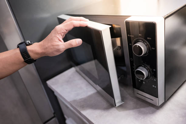 Male hand opening microwave door Male hand opening microwave door in the kitchen showroom. Buying cooking appliance for domestic kitchen. Home improvement concept microwave stock pictures, royalty-free photos & images