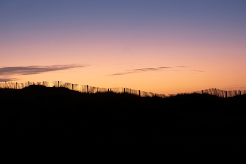 A long fence running along the Devon coastline at sunset, UK