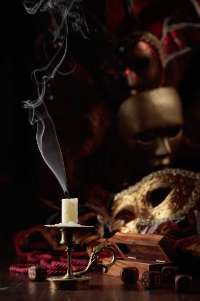 istock Extinguished candle, dice, and carnival masks on an old wooden table. 1444759367