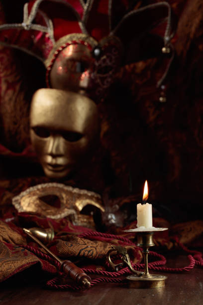 istock Burning candle in an old brass candlestick and carnival masks. 1444759377