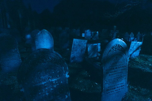 Old gravestones lit up by the moon in a cemetary
