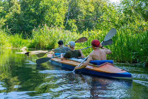 Ulyanovsk, Russia - August 07, 2022: A group of three people paddle in a kayak.  Rafting on the fast river. Adventure traveling lifestyle. Active weekend vacations wild nature outdoor. The canoeing.