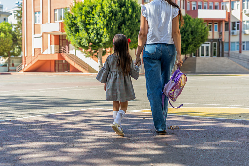 Mother and schoolgirl daughter walking to school