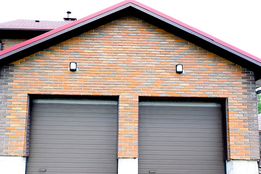 New modern parking garage in residential luxury brick house for two cars construction with roller shutters on gates.