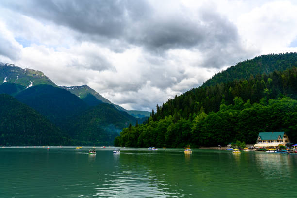 lac alpin ritsa. touristes en catamaran naviguant le long du lac parmi les montagnes. - italian lake district photos et images de collection