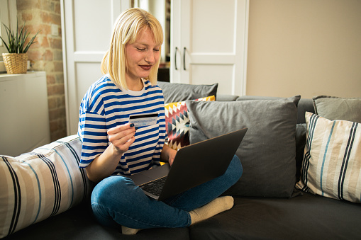 Portrait of a young woman relaxing at home and shopping online using a laptop
