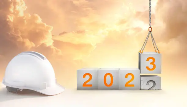 construction start working in the new year 2023. Success real estate, teamwork. Construction-crane lifting the cube and number 3 replace the year 2022 with golden sky in the background.