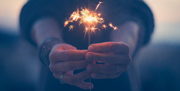 Close up of woman hands holding sparkler light in foreground. Banner image with celebration concept. New year eve and anniversary. Night celebrate people with sparkler in outdoor. Day Dreamer female
