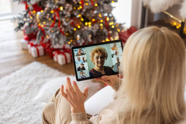 istock Woman using video call conference on tablet in kitchen with ornaments, decorations and lights at home. Caucasian adult showing surprise gift with bow for christmas eve party 1444774968