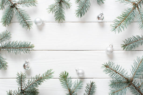 istock Fir branches with Christmas silver glass balls on a white wooden background. 1444775986