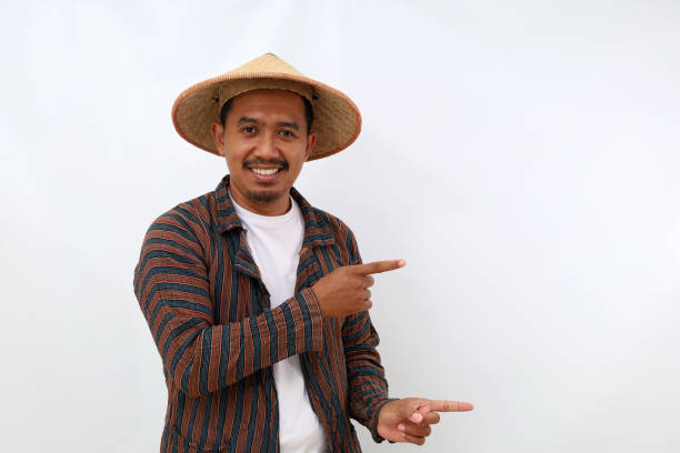 istock Happy asian farmer standing while pointing or presenting something beside. Isolated on white with copyspace 1444793587