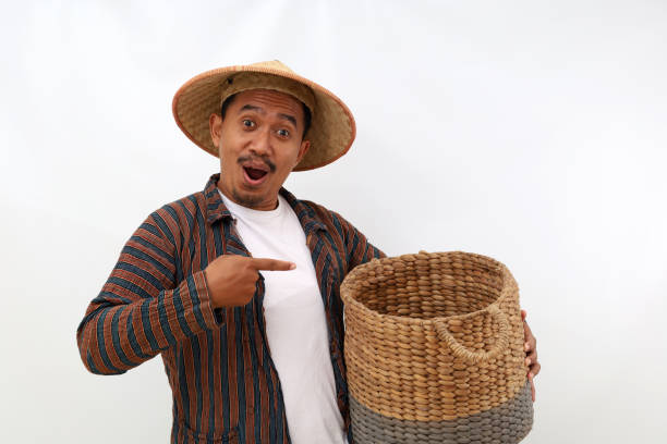 istock Happy asian farmer standing while pointing at empty basket. Isolated on white background 1444794307