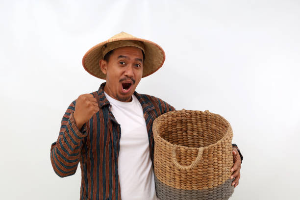 istock Happy asian farmer standing while holding an empty basket and clenching his hand. Isolated on white background 1444794651