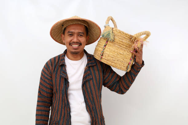 istock Happy asian farmer standing while holding an empty basket on his shoulder. Isolated on white background 1444794655