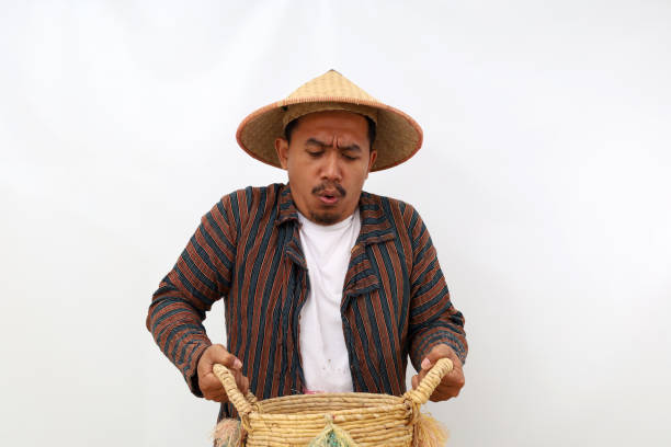 istock Asian farmer standing while holding a heavy basket. Isolated on white background 1444795261