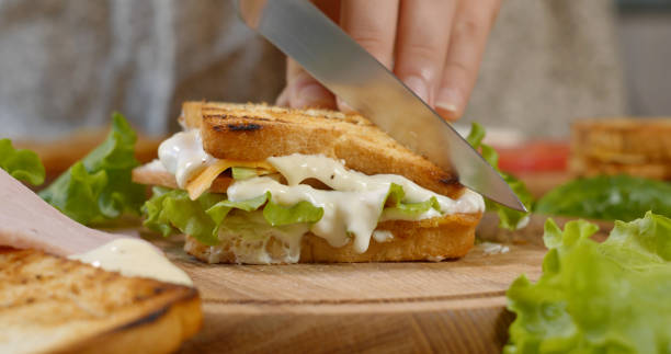 istock A chef cuts a sandwich in half with a sharp knife on a wooden board in the kitchen 1444795421